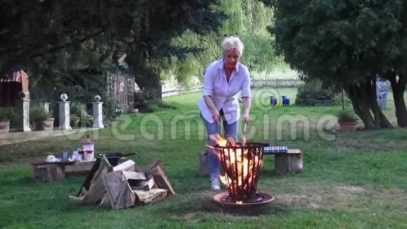 火篮里的火堆是由金发女人准备的烤香肠视频的预览图