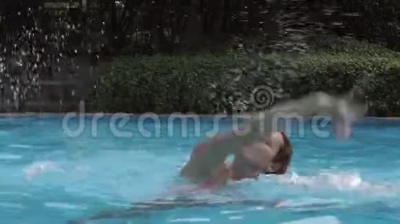 在阳光明媚的夏日戴太阳镜的欧洲女孩在外面的游泳池里溅起蓝色的水视频的预览图