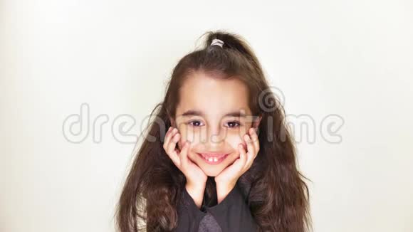一个可爱的白种人小女孩微笑着流露出一种期待的情绪双手捧着她的头肖像白色视频的预览图