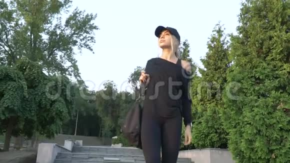 穿着黑色运动服的金发女郎走下公园的台阶视频的预览图