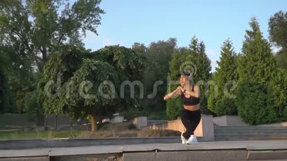 长腿女人在公园里听音乐和训练慢动作视频的预览图