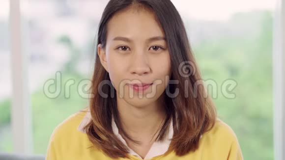 慢动作十几岁的亚洲妇女感到快乐微笑看着相机而放松在她的客厅在家里视频的预览图