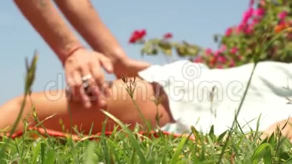 泰国按摩师在户外为女性腿部做按摩男性按摩师为肌肉放松做瑜伽按摩视频的预览图