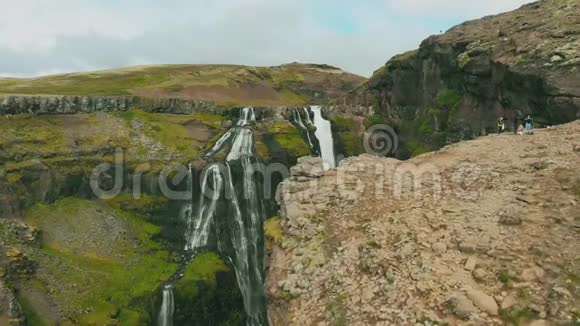 冰岛飞过一个雕文瀑布的空中一个女孩坐在悬崖附近视频的预览图