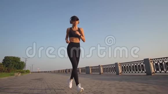 一个穿运动鞋的女人在黎明时跑步听音乐慢动作视频的预览图