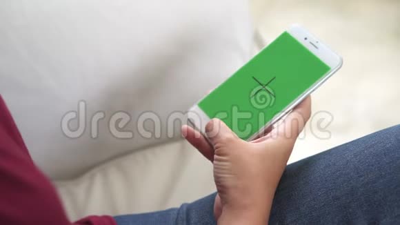 年轻的亚洲女性使用带有绿色屏幕的白色智能手机设备视频的预览图
