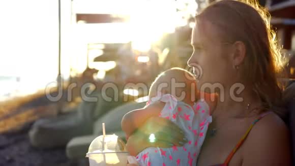 带着女儿的女人在海滩上放松喝了冰饮料视频的预览图