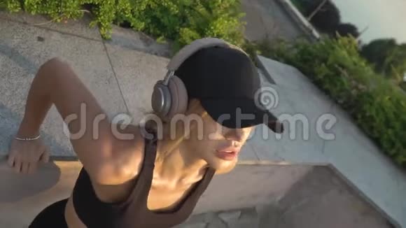 一位戴着耳机在河边公园练习的女士的俯视图视频的预览图
