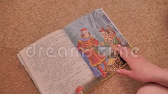 女孩在地板上翻阅一本五颜六色的书她翻开书页看着课文培训视频的预览图