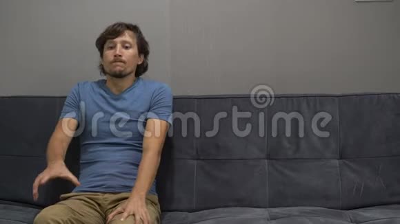 一个年轻人坐在沙发上感到沮丧和恐惧右侧复制空间视频的预览图