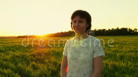 一个女孩站在绿色草坪上在日落的背景下缓慢的动作视频的预览图