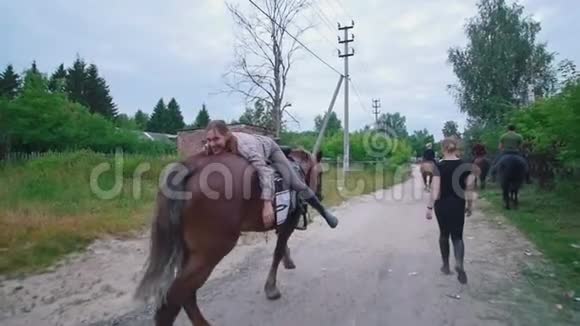 快乐的年轻女子躺在马背上走过乡间小路视频的预览图
