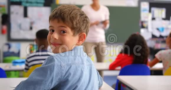 快乐白人小学生在教室里看摄像机的后视图视频的预览图