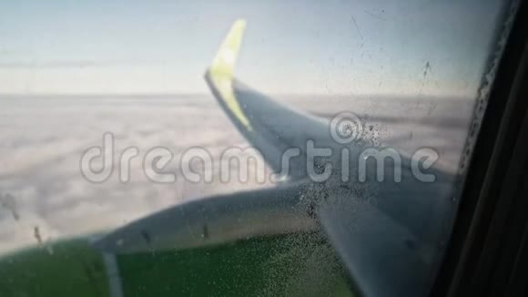 透过窗户看到飞机机翼和云层上有小水滴和一些灰尘视频的预览图
