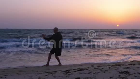 运动员在日落时分在海上练习太极视频的预览图