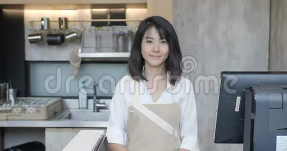 亚洲女咖啡师双手交叉的肖像在咖啡厅的镜头上微笑视频的预览图