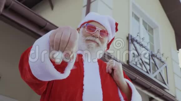 戴着粉色眼镜的圣诞老人摇着新房子的钥匙视频的预览图