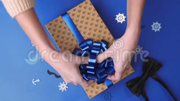 为男人把蝴蝶结粘到现在的盒子里包裹装饰带礼物的盒子视频的预览图