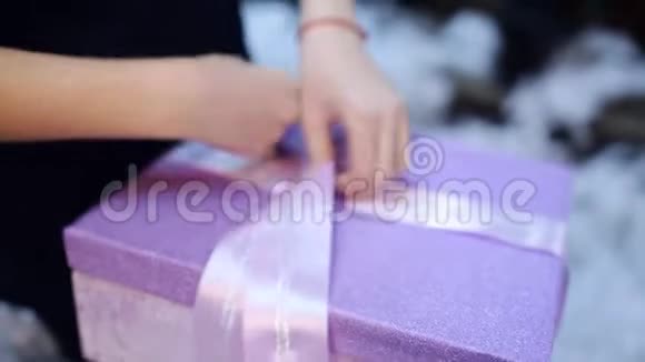 女孩用圣诞礼物在盒子上系一条彩带视频的预览图