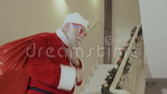 圣诞老人带着一大袋红色的礼物悄悄地溜进屋子视频的预览图