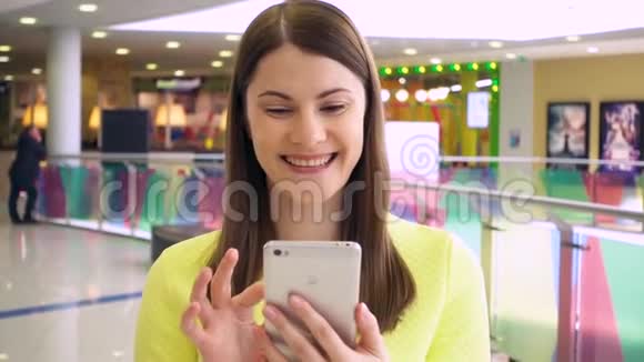 漂亮的女人带着智能手机在商场里慢动作行走浏览互联网和聊天视频的预览图