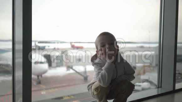 小男孩坐在机场候机楼的窗口等待登机视频的预览图
