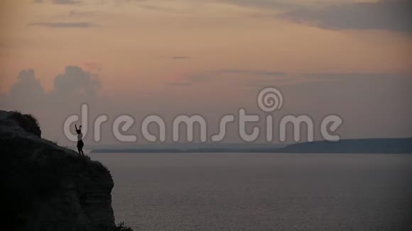 日落时分一位留着黑色长裙长发的女子在悬崖边跳舞视频的预览图
