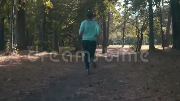 阳光明媚的夏天年轻的女人在树林里奔跑视频的预览图