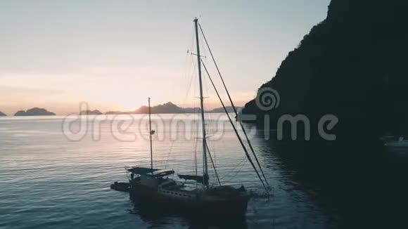 空中无人驾驶飞机观帆船停泊在海湾与清澈和绿松石水在日落帆船游艇视频的预览图