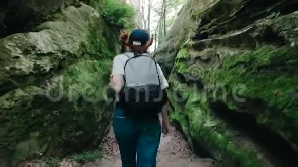 在山里徒步旅行一位年轻的曲棍球女子背着背包行走的后景视频的预览图