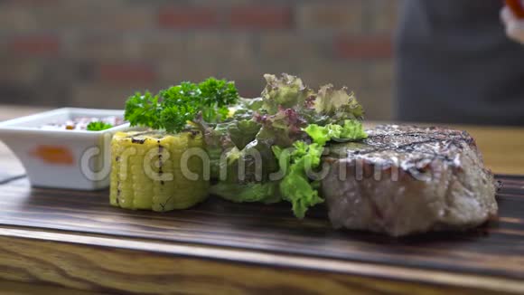 烧烤肉牛排用红辣椒草本植物玉米和番茄酱在木板上把牛排烤熟食物视频的预览图