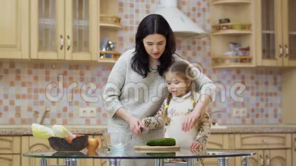 年轻的母亲教她可爱的女儿切黄瓜做沙拉视频的预览图