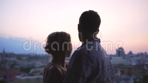 新婚夫妇站在高楼的屋顶上欣赏着城市的全景视频的预览图
