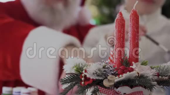 圣诞老人和孩子在红烛的背景下画画视频的预览图