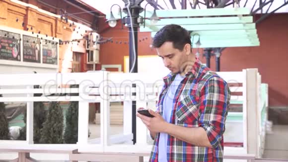 一个穿着衬衫的男人使用智能手机城市景观视频的预览图