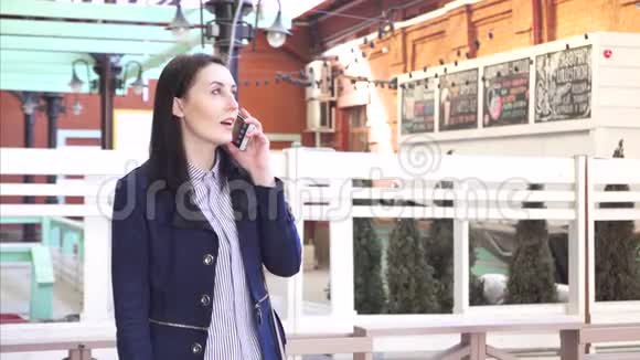 现代黑发女孩通过电话与城市景观沟通视频的预览图