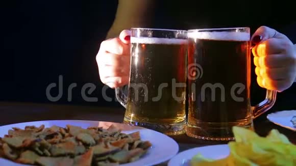 酒保在桌子上放着黑色背景上的零食两杯满是泡沫的啤酒视频的预览图