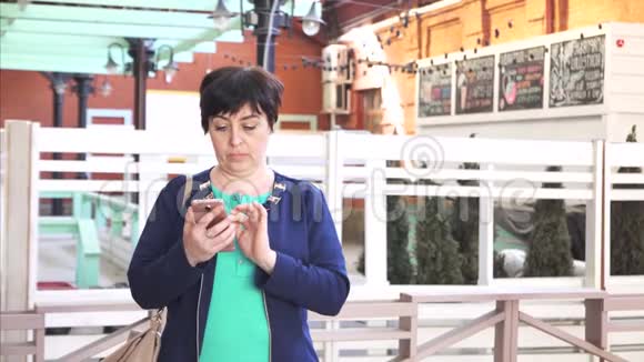 40岁以上的女性享受智能手机城市景观视频的预览图
