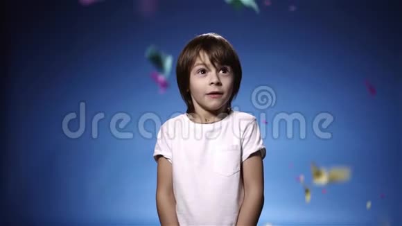 慢动作可爱的小男孩惊讶于饼干和微笑蓝色背景视频的预览图
