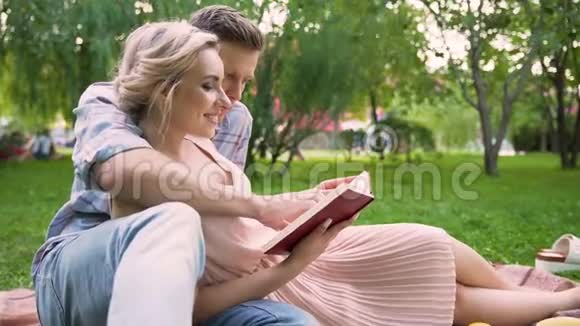 一个爱看故事的人在公园里给他美丽的女士轻轻地吻她视频的预览图