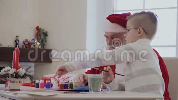 圣诞老人和小孩用丙烯酸涂料画画视频的预览图