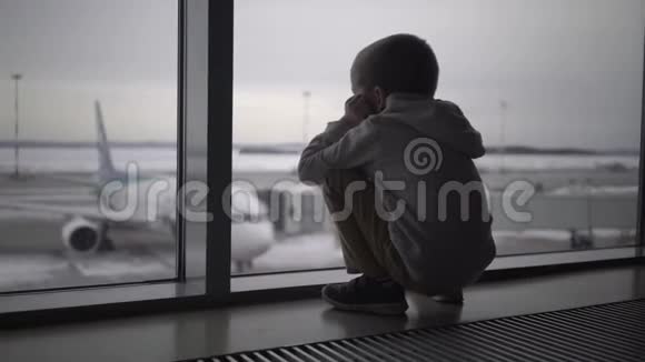 小男孩坐在机场候机楼的窗口等待登机视频的预览图