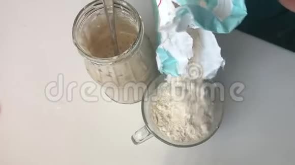 女人在一杯水中加入面粉使面包变酸的混合物酸面包立在一个玻璃罐子旁边视频的预览图