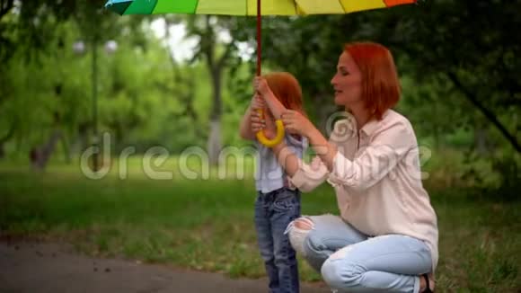 在彩色雨伞下快乐的妈妈和女儿视频的预览图