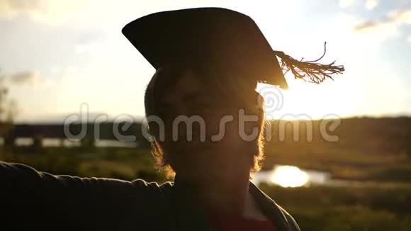 站在夕阳下戴着学生帽的中年妇女剪影视频的预览图