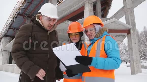 工头和两名女检查员在冬季检查位于他们后面的建筑工地视频的预览图