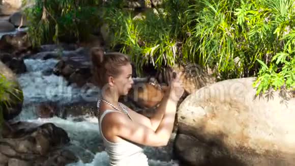 旅游妇女在热带雨林的山瀑布里爬山时在手机上拍照野生自然旅行视频的预览图