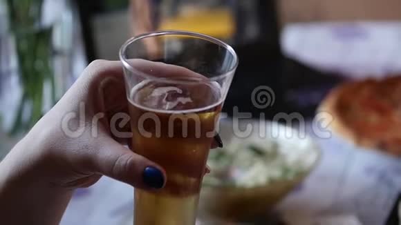 女人手拿着冰冷的淡啤酒盛着水滴的杯子里慢动作视频的预览图