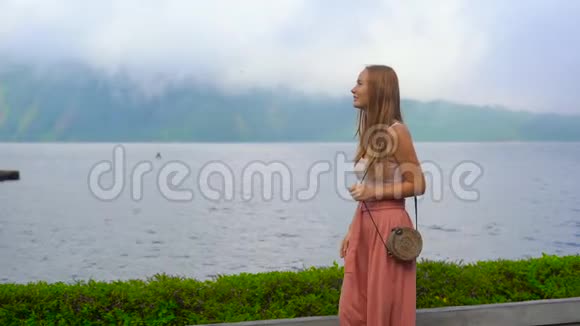 印度尼西亚巴厘岛布拉坦湖上一名年轻女子在普拉乌伦丹努神庙周围行走的慢镜头视频的预览图