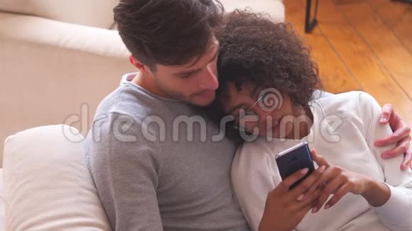 一对轻松的夫妇在家里使用手机视频的预览图